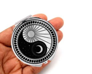 yin yang compact mirror, laying on a woman's hand to show the size.