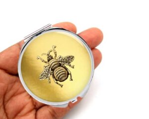 bumble bee compact mirror, laying on a woman's hand to show the size.