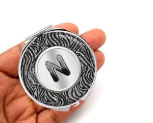 Animal Print Metal pocket mirror, laying on a woman's hand to show the size.