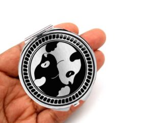 yin yang foldable compact mirror, laying on a woman's hand to show the size.