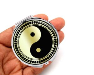 yin yang portable compact mirror, laying on a woman's hand to show the size.