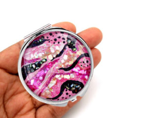 Compact mirror gifts laying on a woman's hand to show the size. Designed by Terlis Designs.