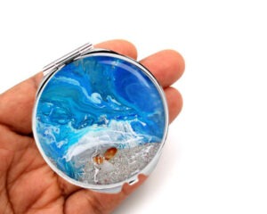 Compact mirror travel gift laying on a woman's hand to show the size. Designed by Terlis Designs.