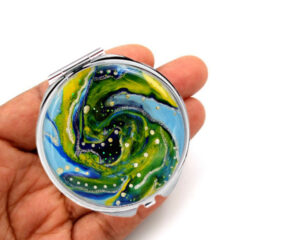 Custom floral compact mirror laying on a woman's hand to show the size. Designed by Terlis Designs.