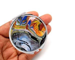 Custom travel compact mirror laying on a woman's hand to show the size. Designed by Terlis Designs.