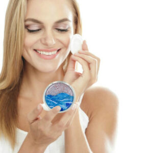 Silver compact mirror being used by a woman applying makeup. Created by Terlis Designs.