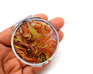 Small makeup mirror laying on a woman's hand to show the size. Designed by Terlis Designs.
