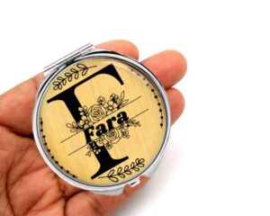 Personalized initial compact mirror, laying on a woman's hand to show the size.