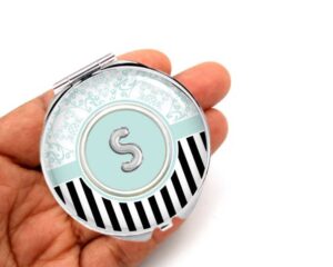 black stripe portable mirror, laying on a woman's hand to show the size.