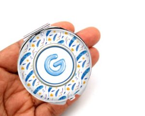 sky blue floral print pocket mirror, laying on a woman's hand to show the size.