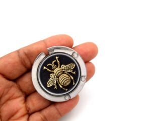 Bumble bee handbag hanger, item SKU PURH406, laying on a woman's hand to show the size image by Terlis Designs.
