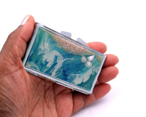 Metal Pill Case - PILB179, laying on a woman's hand to show the size, image by Terlis Designs.