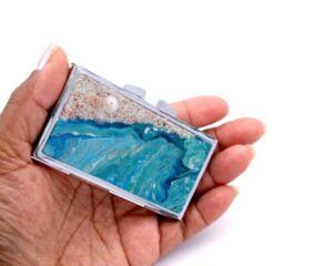 Ocean art Pill Organizer - PILB59, laying on a woman's hand to show the size, image by Terlis Designs.