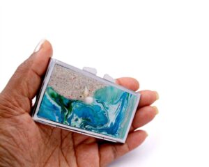 Ocean art Portable Pill Organizer - PILB60, laying on a woman's hand to show the size, image by Terlis Designs.