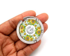 Sunflower magnetic bag hanger, item sku PURH462B, laying on a woman's hand to show the size image by Terlis Designs.