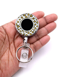 Gold White Animal Print nursing badge reel - BADR452B - laying on a woman's hand to show the size. Designed By Terlis Designs.