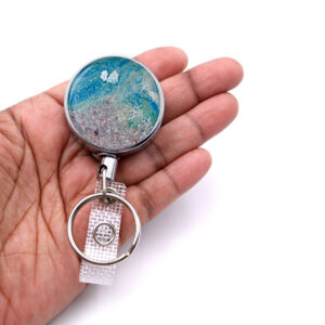 Monogram badge reel - BADR442 - laying on a woman's hand to show the size. Designed By Terlis Designs.