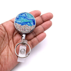 Ocean teacher badge reel - BADR382 - laying on a woman's hand to show the size. Designed By Terlis Designs.