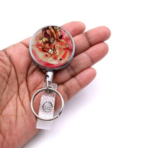 Retractable badge clip - BADR32 - laying on a woman's hand to show the size. Designed By Terlis Designs.