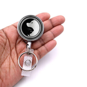 Yin Yang retractable badge clip gift - BADR418S2B - laying on a woman's hand to show the size. Designed By Terlis Designs.